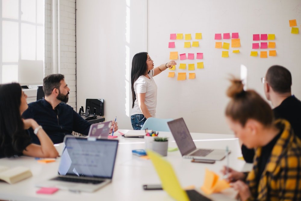 Team di lavoro in riunione davanti a una lavagna di post-it colorati